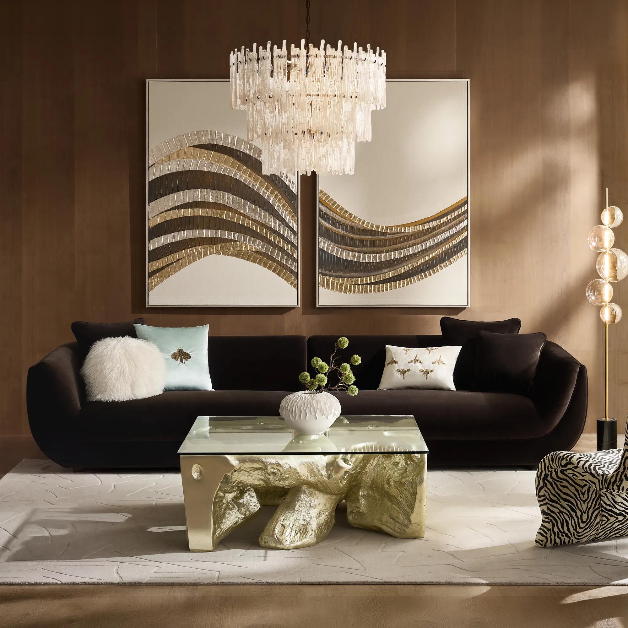 Dark chocolate Curvia sofa with decorative pillows beneath paired abstract artworks and a glass chandelier in a Z Gallerie living room.